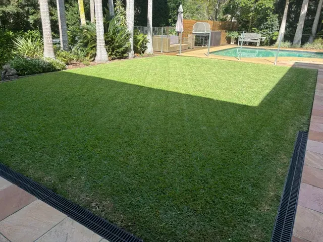 Poolside lawn mowed and edged along a paved path